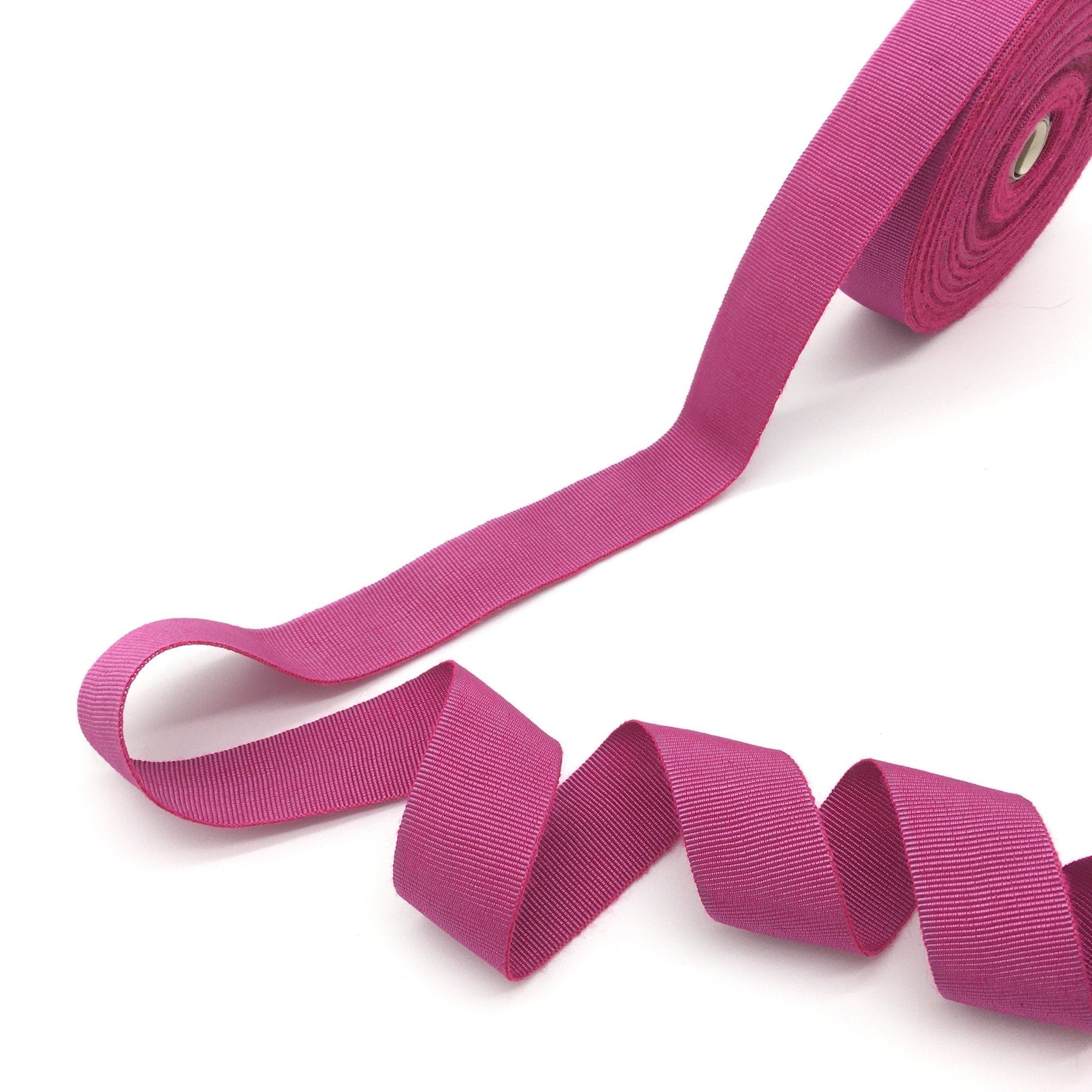 A roll of pink grosgrain ribbon with a ribbed texture.