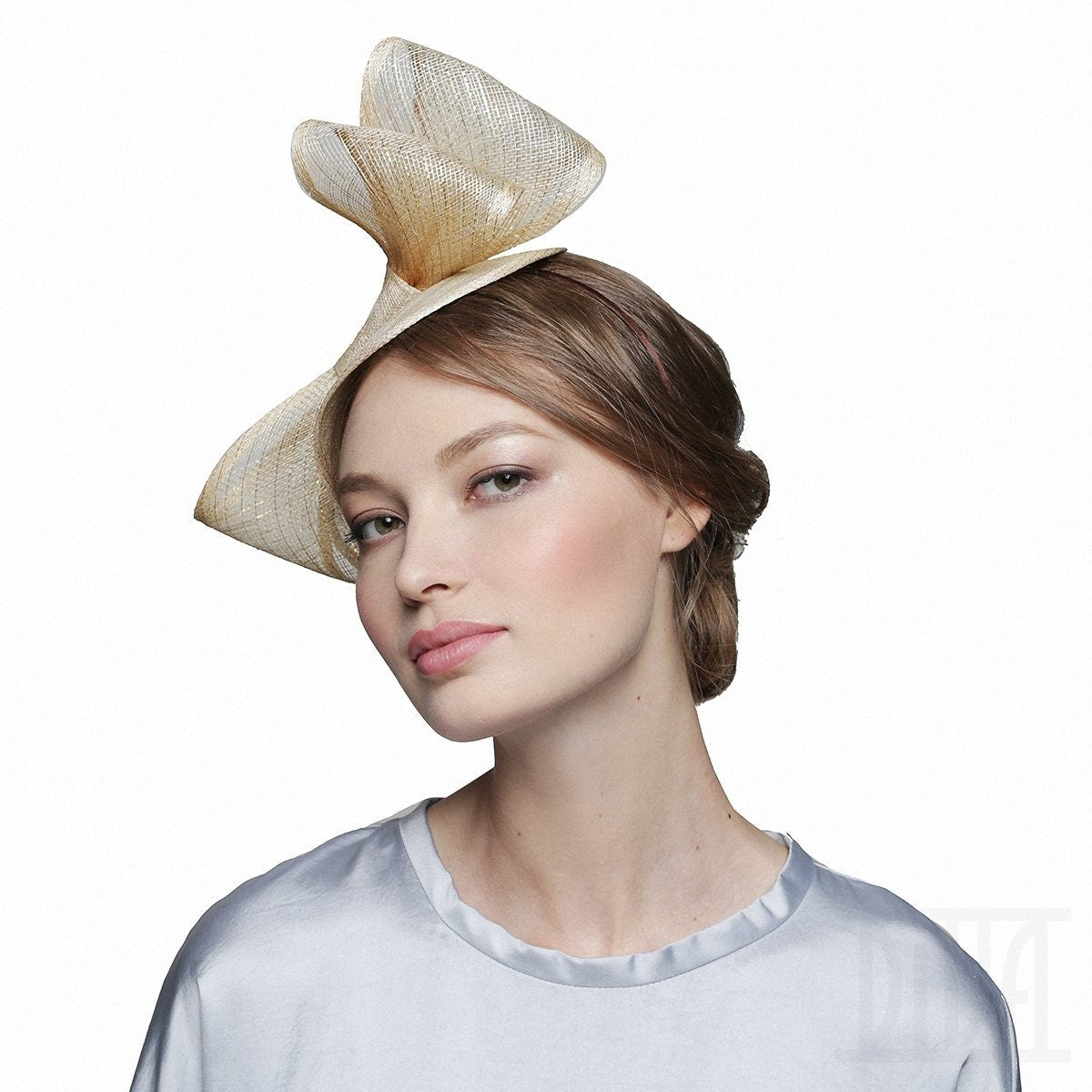 A gold straw hat with a unique, asymmetrical design.