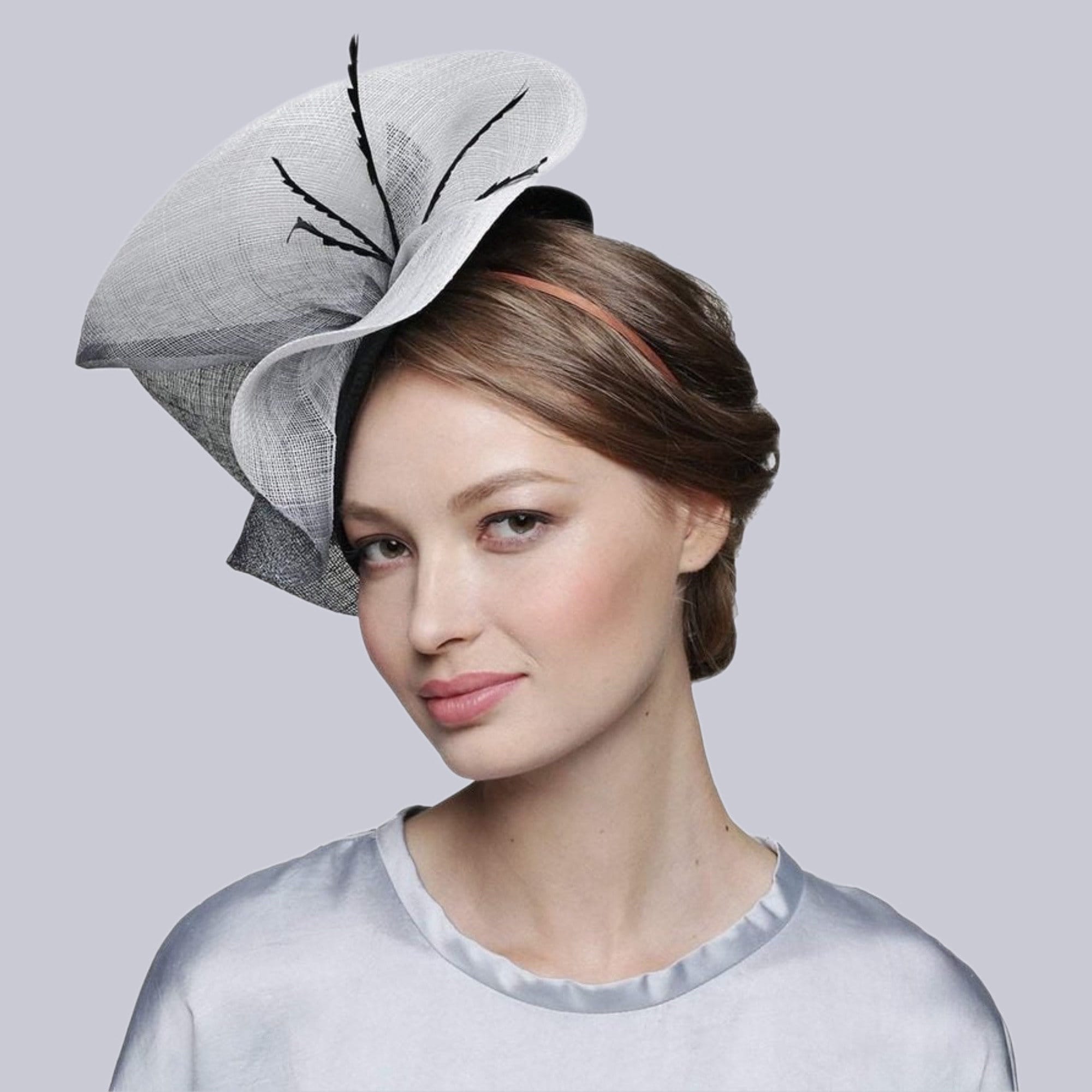 A black and white fascinator hat with a large black bow. The hat is made of a delicate material.