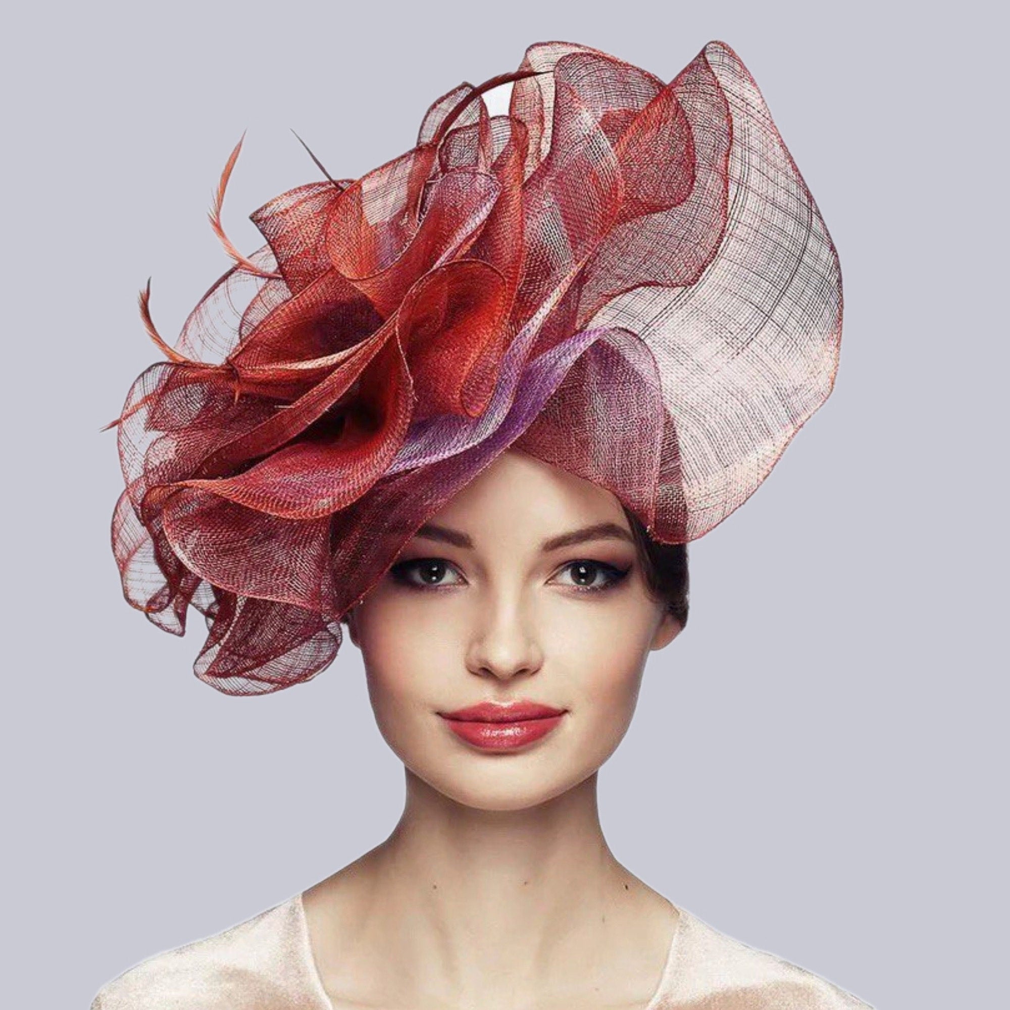 Oversized headpiece. The hat features layers of sheer, ruffled fabric in shades of red, burgundy, and purple. The headpiece is an eye-catching accessory, perfect for special occasions.