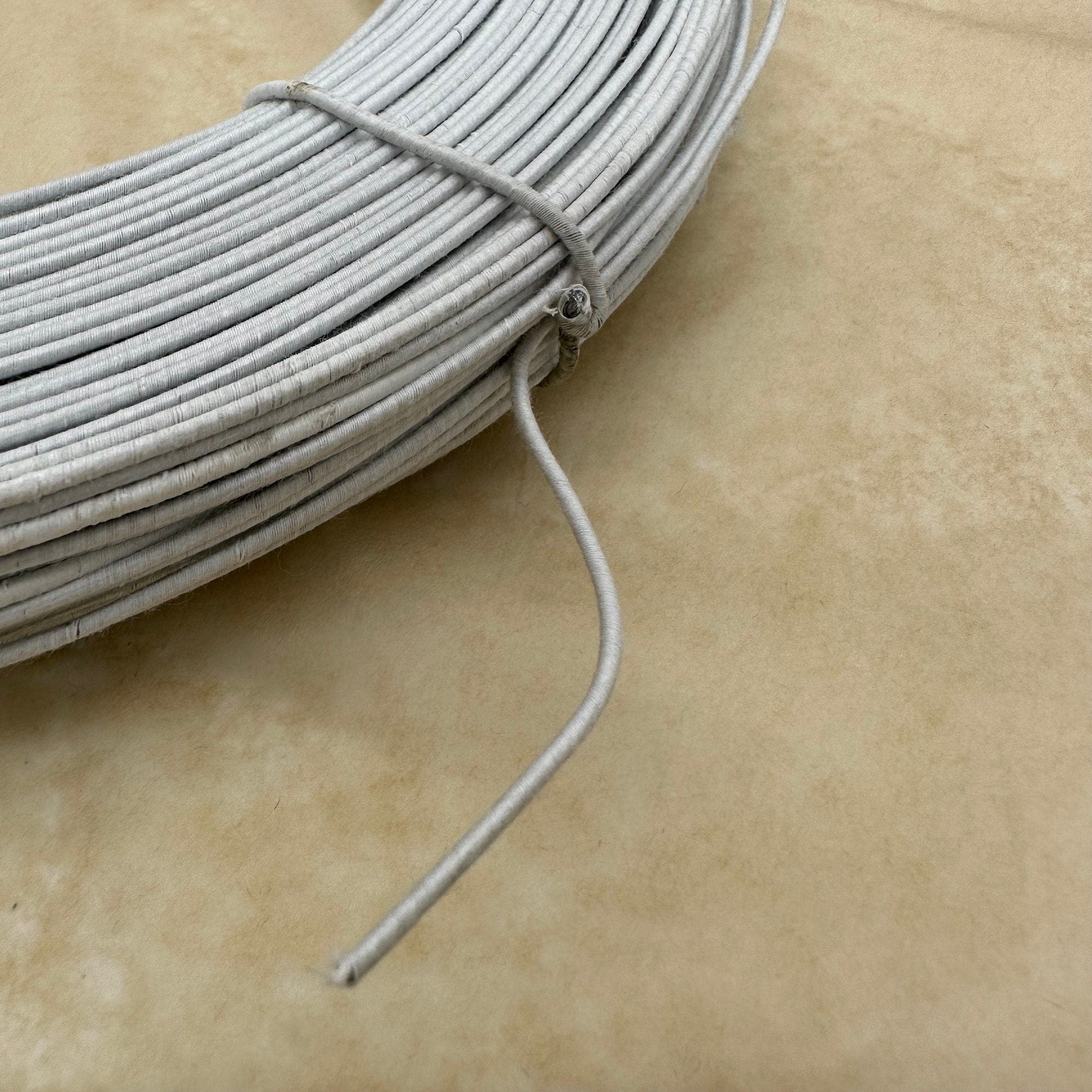 White wire, wrapped in a coil. The wire is thin and flexible, and it is likely used for crafts or other projects.
