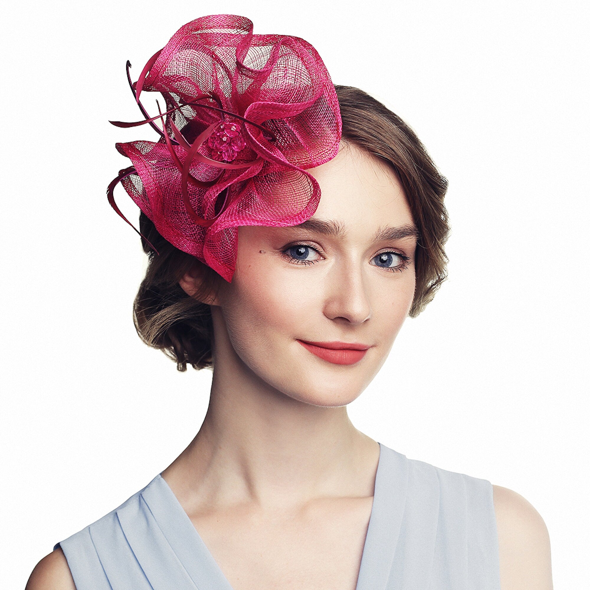 Fuchsia-colored fascinator with a layered, floral design. The headpiece features a central cluster of small, sparkling embellishments and delicate, curling accents.