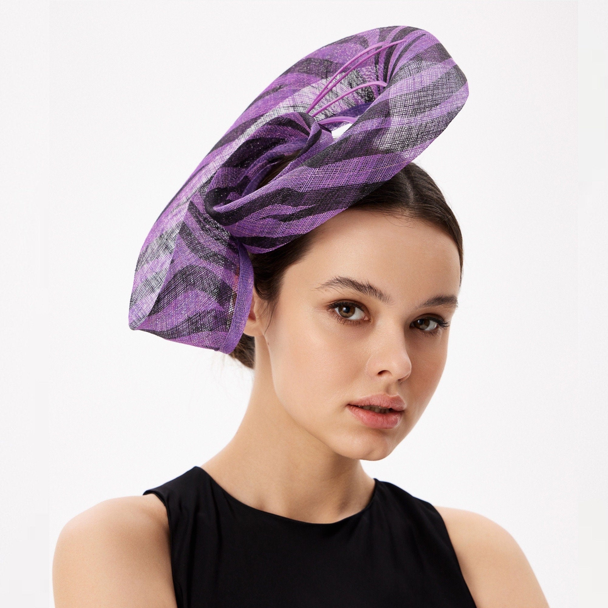 Purple and black patterned headpiece. The headpiece is a large, decorative accessory with a curved, bow-like design. The fabric has a zebra-like pattern in shades of purple and black. The accessory is worn on the head.
