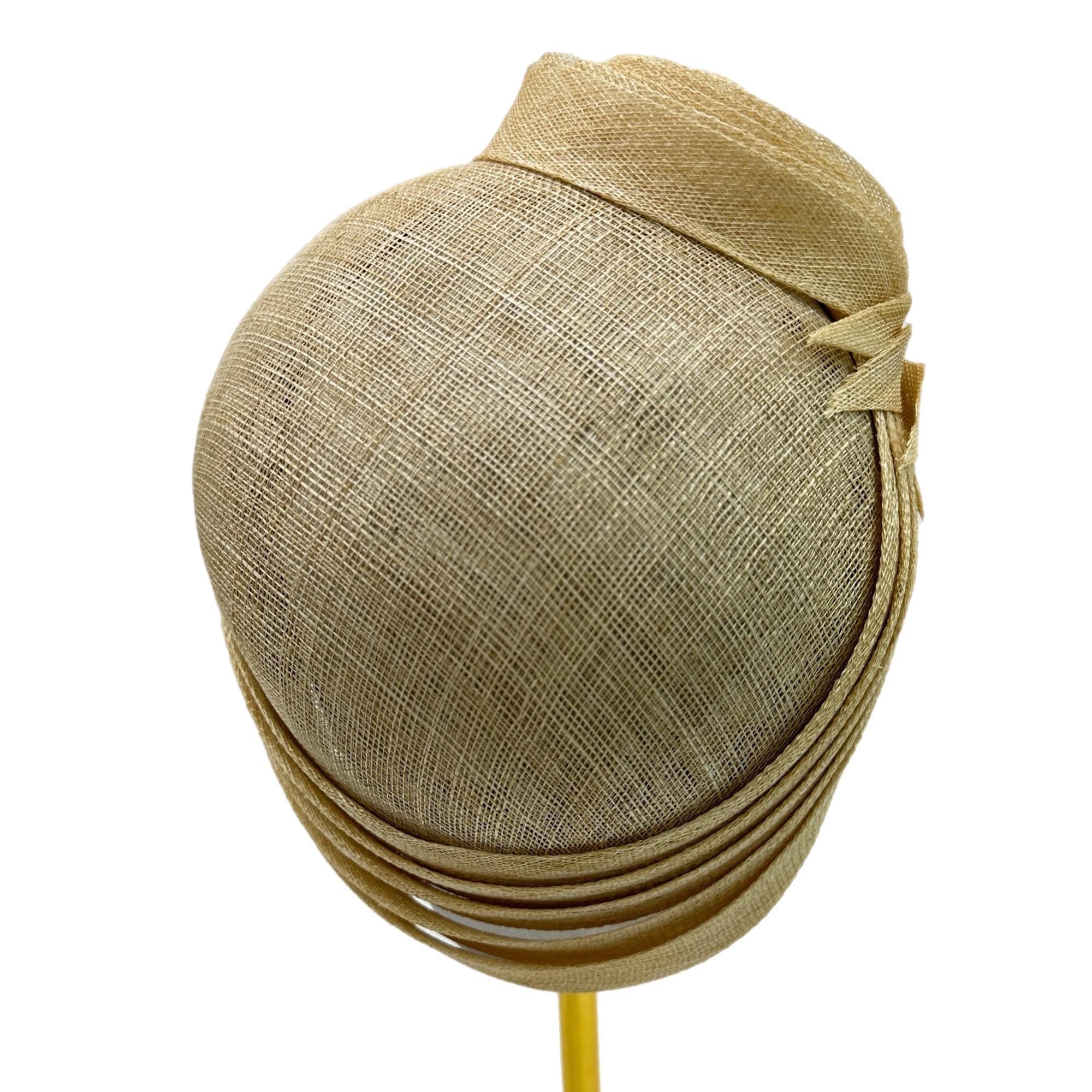Beige straw hat with a wide brim and a decorative bow on the side. The hat is sitting on a yellow stand.
