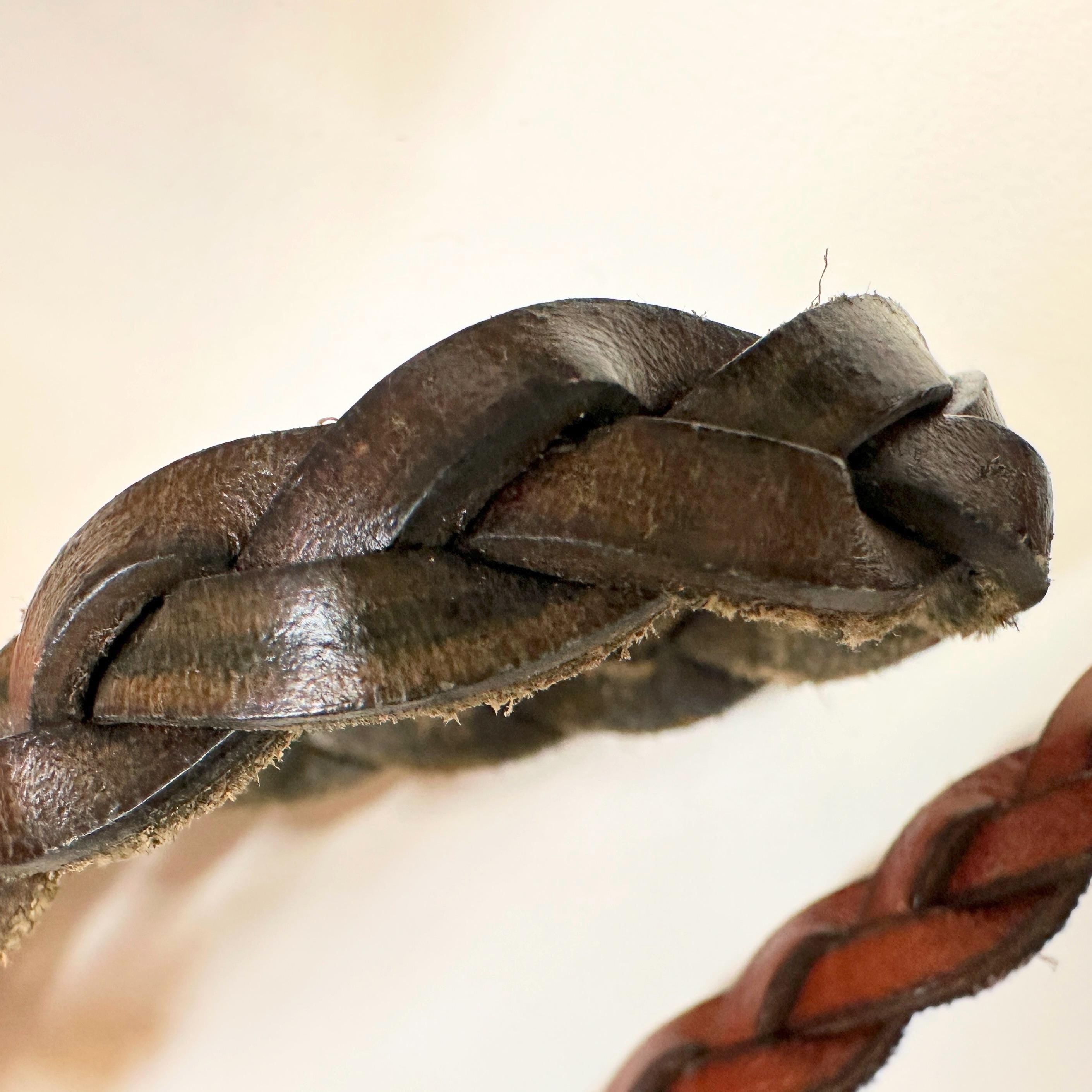 Close-up of a green leather braided strap. The strap is woven in a simple braid pattern.