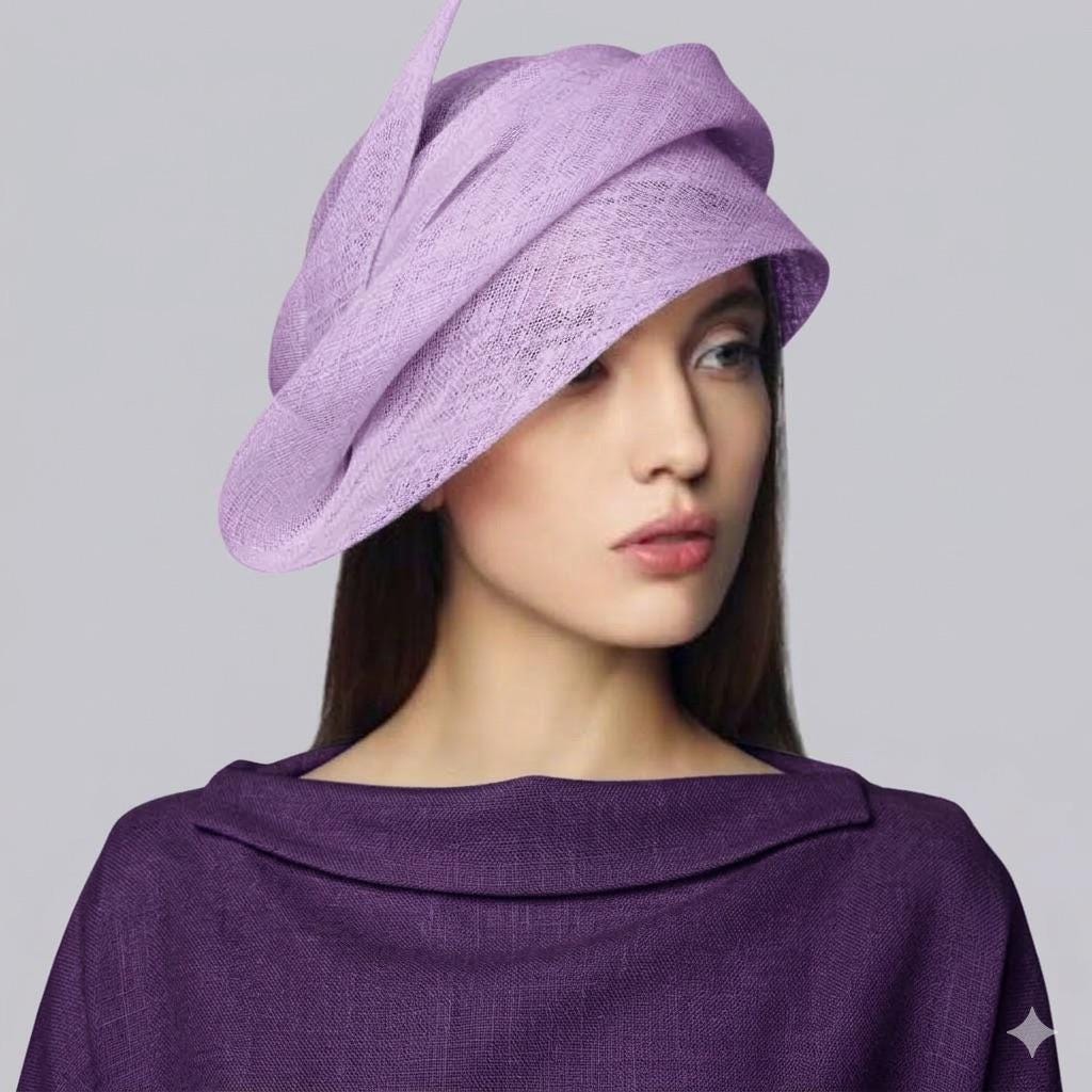 Elegant woman wearing a sculptural lavender sinamay straw couture hat with a sweeping wide brim for wedding guest style.
